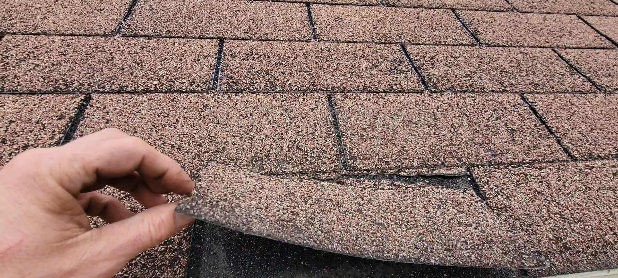 nc roofer lifting up shingle to show rot