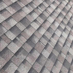 photograph of roof shingles. grey shingles with darker and lighter spots.