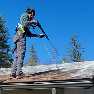 roofer on roof. spraying roof restoration solution.